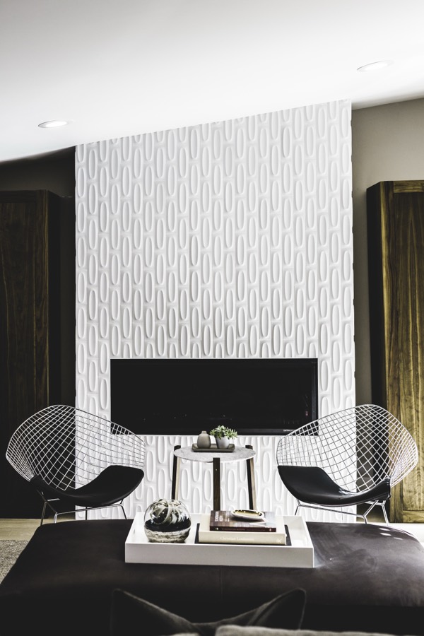 Modern interior with a sculpted fireplace wall and wire chairs