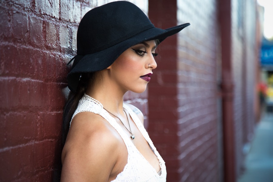 Editorial profile in a wide-brim black hat against brick